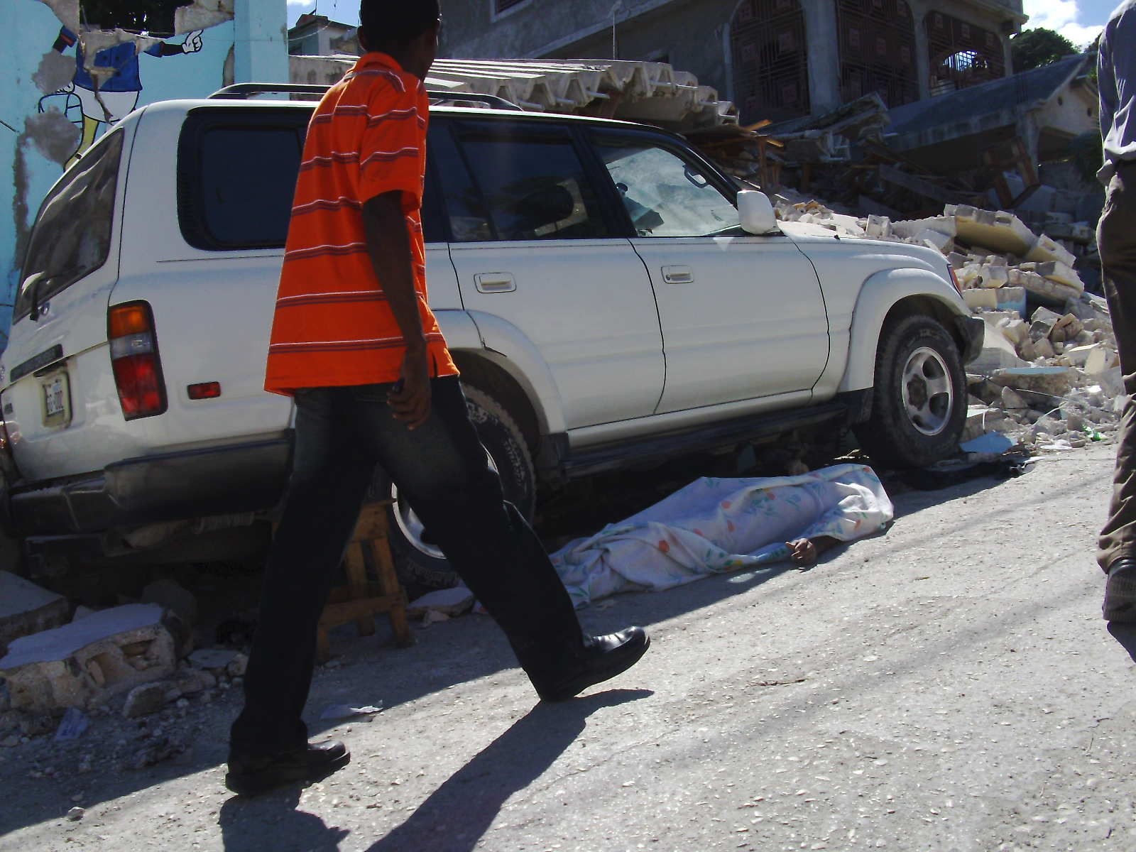 A body lies covered in the street.